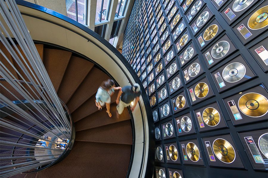 Guests walk down a spiral staircase past records at the Country Music Hall of Fame.